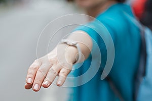 Woman walking in City, turning around and making a follow sign to the camera.