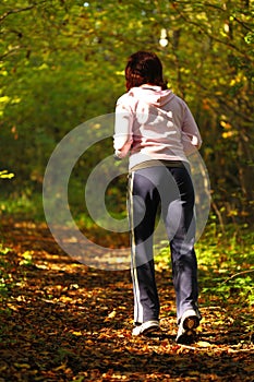 Woman walking cross country trail in autumn forest