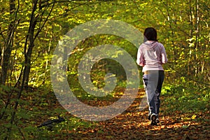 Woman walking cross country trail in autumn forest