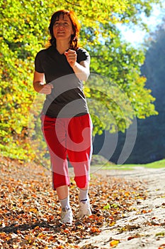 Woman walking cross country trail in autumn forest