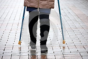 Woman walking with crutches on a city street