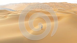 Woman walking on the desert sand dunes aerial view