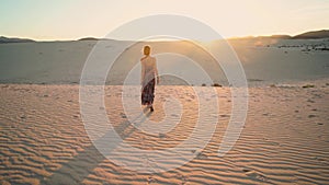 Woman walking on the desert during sunset, relaxing. Calm girl.