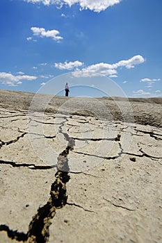 Woman walking on desolate cracked earth landscape