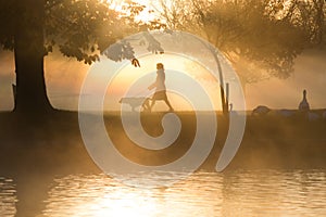 Early morning mist and fog over lake with passers by