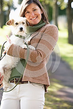 Woman Walking Dog Outdoors In Autumn Park
