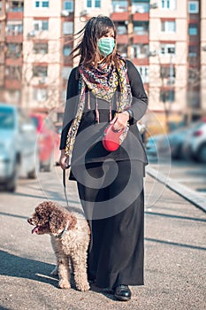 woman walking dog in the street with face mask