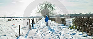 Woman walking in dutch rural winter landscape.