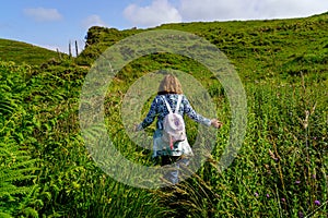 Woman walking through the field among flowers and green grass in summer. Santander