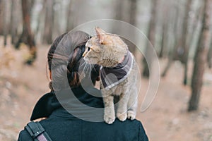 Woman walking the forest with cute kitten on her shoulder.