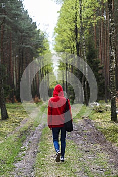 A woman walking in the forest in a red hood