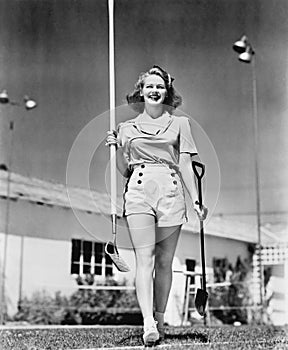 Woman walking with a garden shovel and hoe