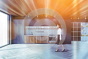 Woman walking in gray kitchen with cupboards