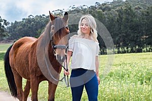 Woman walking her chestnut Arab horse outdoors