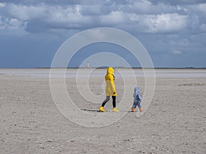 Woman is walking with her child on the beach at the North Sea