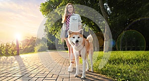 Woman walking her cute Akita Inu dog in park on sunny day, banner design. Lovely pet