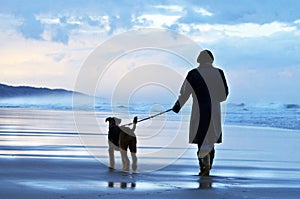 Woman walking her dog at sunset on deserted Australian beach