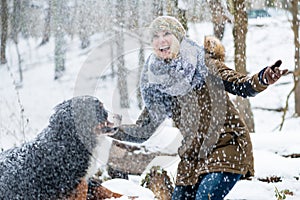 Woman walking her dog in the winter and both explore the snow to