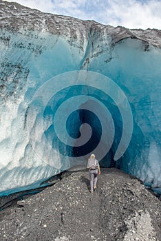 A woman walking into an ice cave in Alaska wilderness