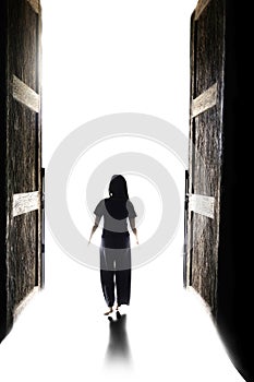 Woman walking into the light through open big door