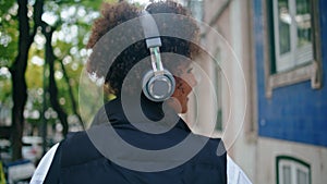 Woman walking listening music in headphones close up. African girl in earphones