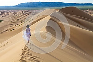 Woman walking in the mongolian desert sand dunes. Young woman walking golden sand on a bright summer day, Mongolia