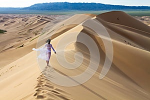 Woman walking in the mongolian desert sand dunes. Young woman walking golden sand on a bright summer day, Mongolia