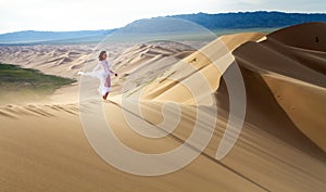 Woman walking in the mongolian desert sand dunes. Young woman walking golden sand on a bright summer day, Mongolia