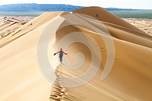 Woman walking in the mongolian desert sand dunes. Young woman walking golden sand on a bright summer day, Mongolia