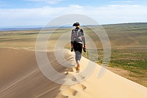 Woman walking in the mongolian desert sand dunes. Young woman walking golden sand on a bright summer day, Mongolia