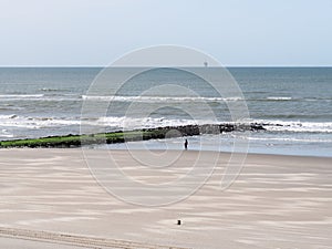 Woman walking near breakwater on beach of North Sea coast of West Frisian island Vlieland, Netherlands photo