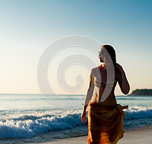 Woman walking near the sea at sunset