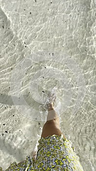 Woman is walking through the ocean with no shoes