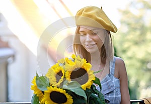 Woman is walking in the old town. He is holding a bouquet of autumn sunflowers in his hand