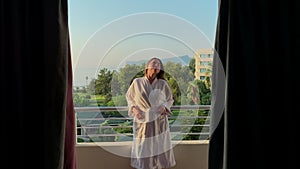 Woman walking out on terrace with view at sea. Enjoying the moment in the early morning.