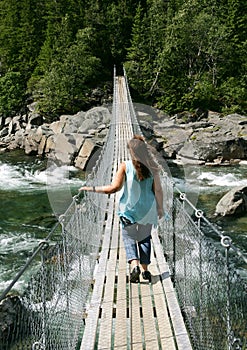 Woman walking over a suspension bridge