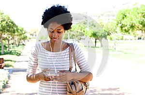 Woman walking in park listening to music on phone
