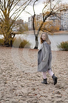 Woman walking in park wearing coat. Cold weather, autumn season