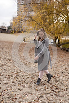 Woman walking in park wearing coat. Cold weather, autumn season