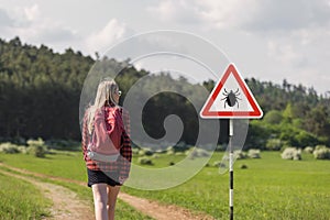 Woman walking past tick Infected area with danger sign