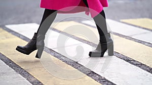 Woman is walking on pedestrian crossing at autumn day, closeup view on feet