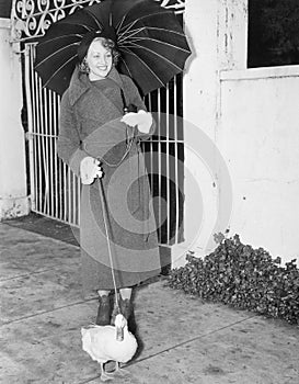 Woman walking in the rain with a duck on a leash