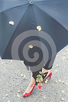 Woman walking in red high heels with a black umbrella