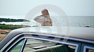 Woman walking retro car at sunny sea coast. Girl traveler relaxing on seashore.