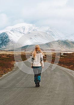 Woman walking on the road to mountains travel hiking