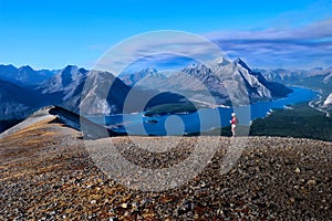 Woman walking on rocks above blue lake in Canadian Rockies.