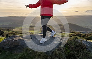 woman walking on a rocks on the mountain trail at cold autumn evening. Hiking and active lifestyle concept