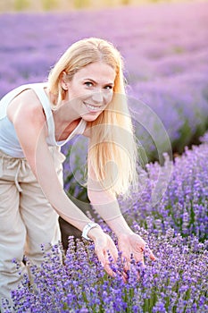Woman walking between rows of lavender flowers and posing