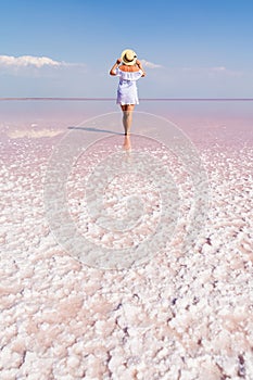Woman walking on salt plains. Water colored with pink algae