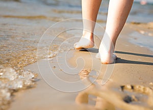 Woman walking on sand beach leaving footprint in the sand. Beach travel